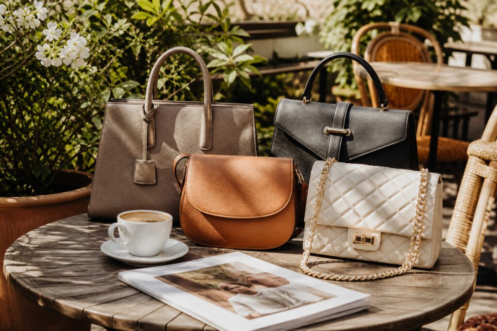 A stylish wooden table at a bustling outdoor café with designer bags.